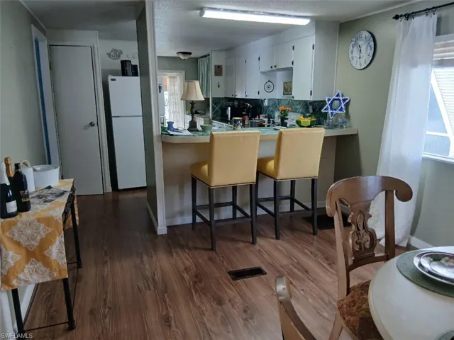 Kitchen with a kitchen bar, light countertops, dark wood finished floors, and backsplash