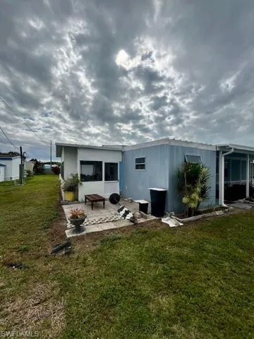 Rear view of house featuring a patio and a lawn