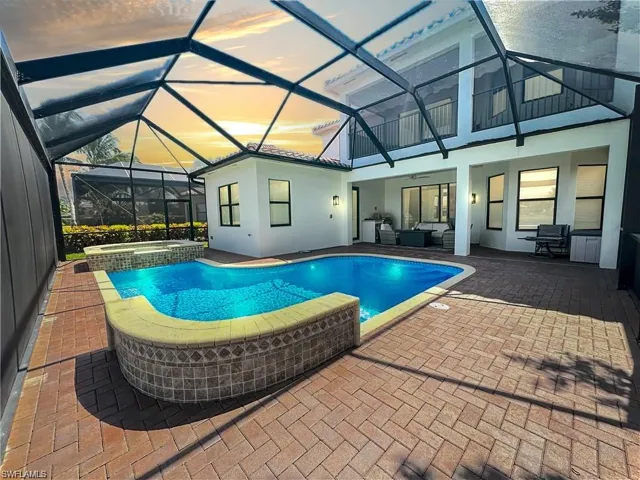 Pool at dusk with a patio, an in ground hot tub, glass enclosure, and ceiling fan