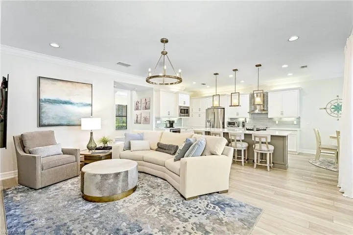 Living room with a notable chandelier, crown molding, and light wood-type flooring
