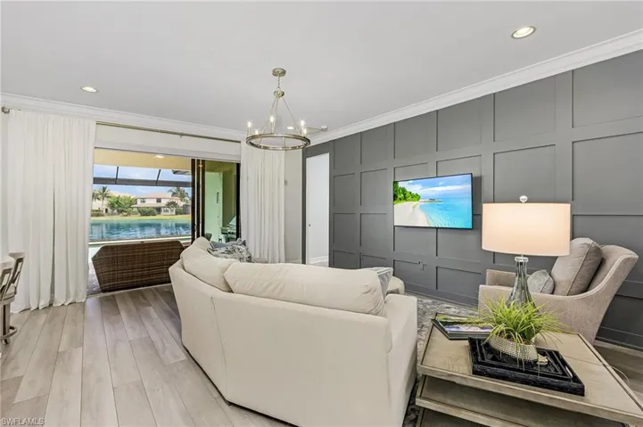 Living room with a notable chandelier, light hardwood / wood-style floors, and crown molding