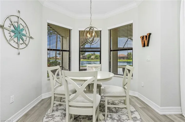 Dining space featuring light wood-type flooring, ornamental molding, a healthy amount of sunlight, and a chandelier