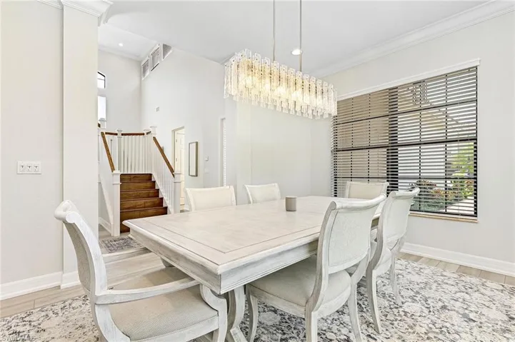 Dining area featuring light wood-type flooring, crown molding, and a chandelier