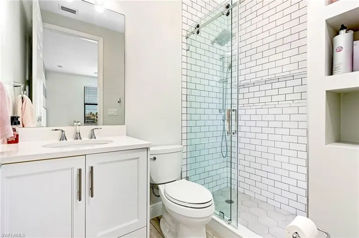 Bathroom featuring a shower with door, toilet, vanity, and built in features
