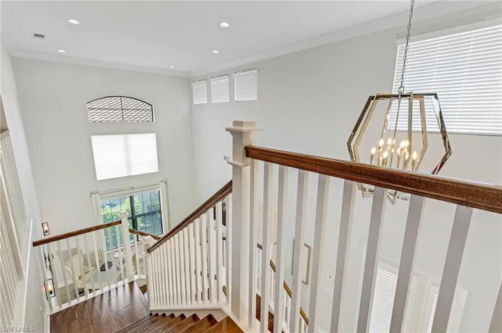Staircase featuring a high ceiling, crown molding, an inviting chandelier, and wood-type flooring