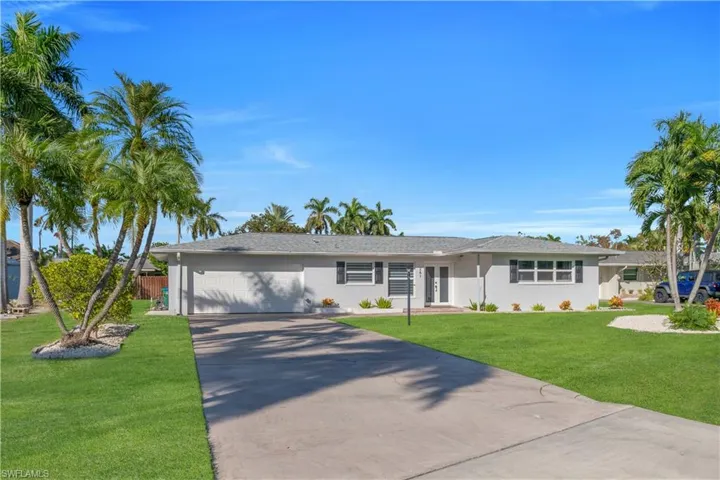 Ranch-style house featuring a front lawn, concrete driveway, an attached garage, and stucco siding