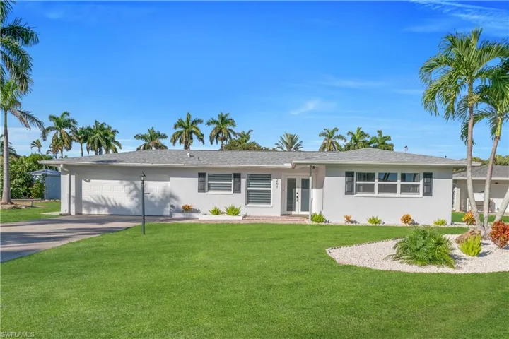 Ranch-style house featuring an attached garage, a front yard, concrete driveway, french doors, and stucco siding