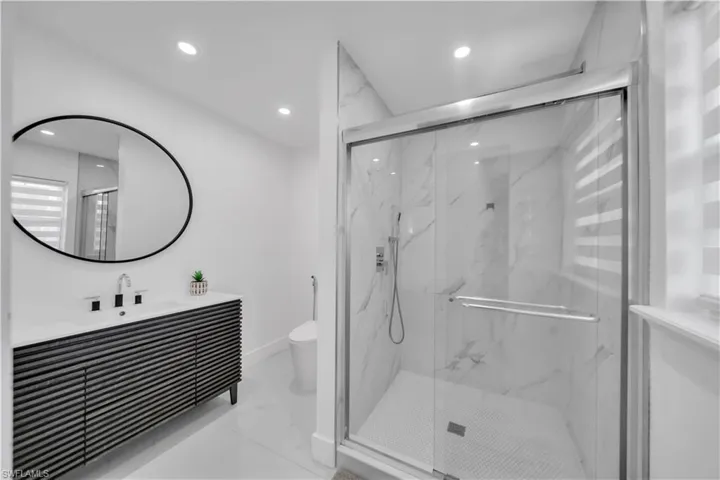 Full bathroom with a marble finish shower, vanity, recessed lighting, and light marble finish flooring
