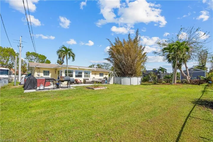 Spacious fenced back yard includes a patio with hot tub and above ground pool