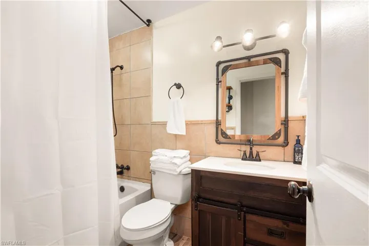 Full guest updated bathroom featuring vanity, toilet, tile walls, and shower / tub combo