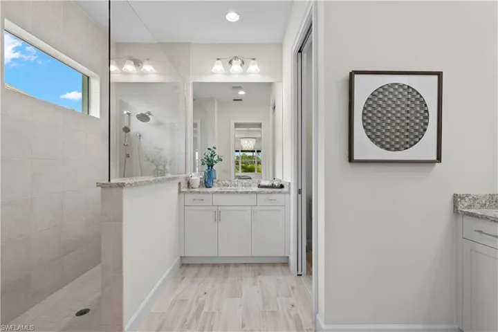 Owners suite bathroom featuring tiled shower, double separate vanity, and a wealth of natural light