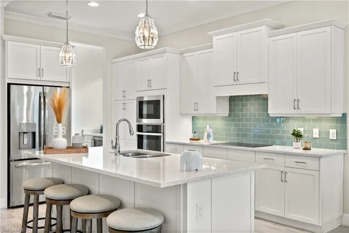 Kitchen with sink, stainless steel appliances, backsplash, and an island with sink