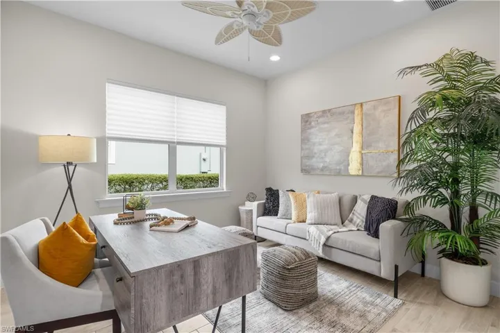 Den with light wood-type tile flooring, ceiling fan, and motorized shades