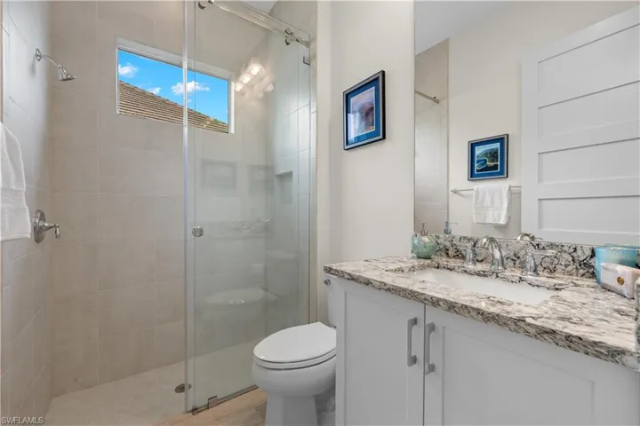 Guest bathroom with a shower with glass shower door, toilet, and vanity
