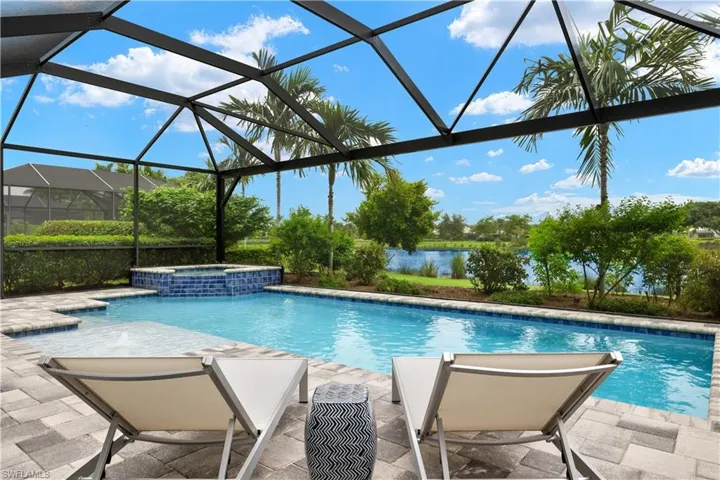 View of pool with an in ground hot tub, and full picture window screen enclosure