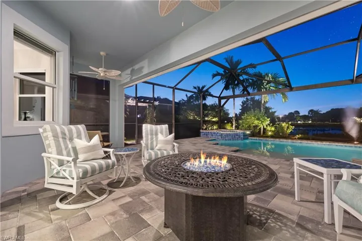Patio terrace at dusk featuring ceiling fan and an outdoor fire pit, and storm smart screens