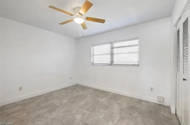 Room with wood-finish ceiling fan, window with horizontal blinds, and louvered bifold closet doors