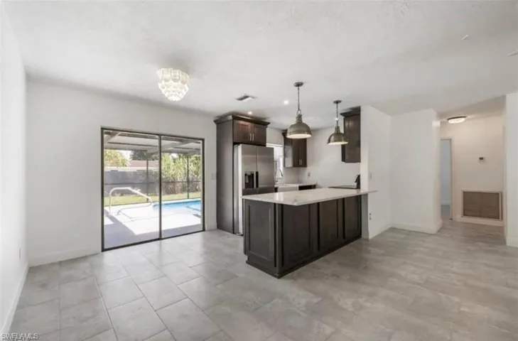 Expansive living space featuring large format tile flooring and direct access to the screened-in patio and swimming pool