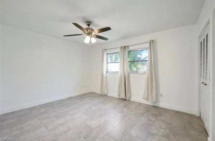 Room with light-toned tiled flooring, white walls, and a ceiling fan with integrated lighting
