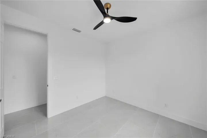 Spare room featuring a ceiling fan, visible vents, and baseboards
