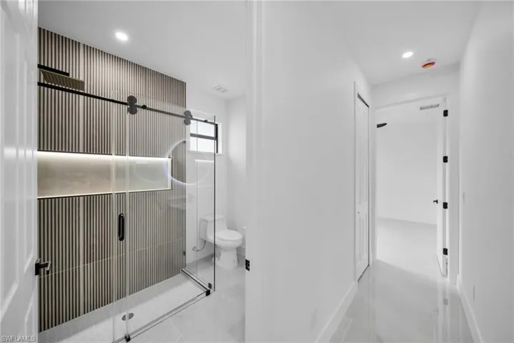Bathroom with toilet, a stall shower, and recessed lighting