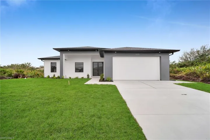 Prairie-style home with a garage, driveway, a front lawn, and stucco siding