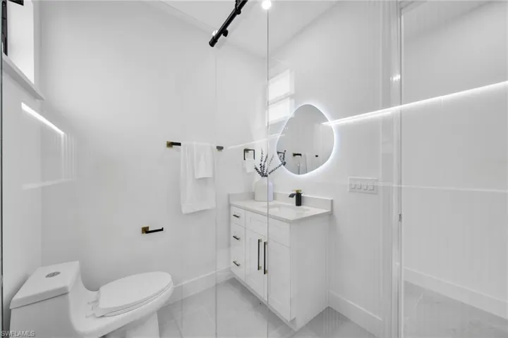 Bathroom featuring toilet, marble finish floor, and vanity