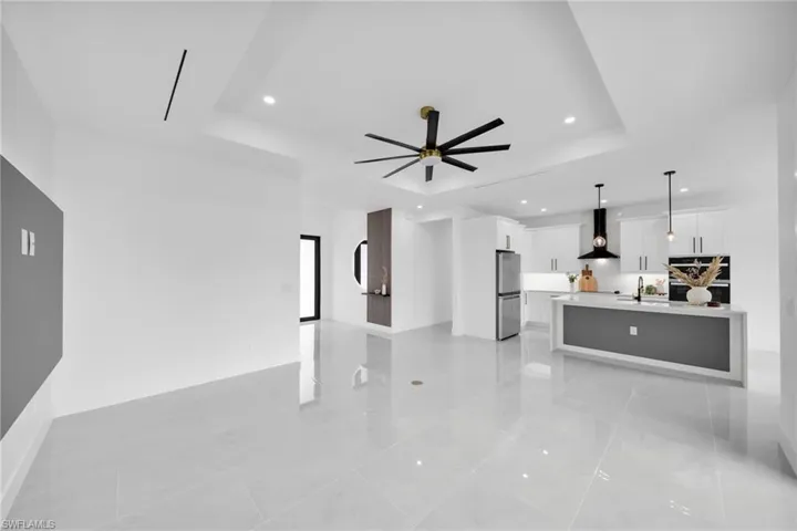 Living room with a tray ceiling, recessed lighting, a ceiling fan, and baseboards