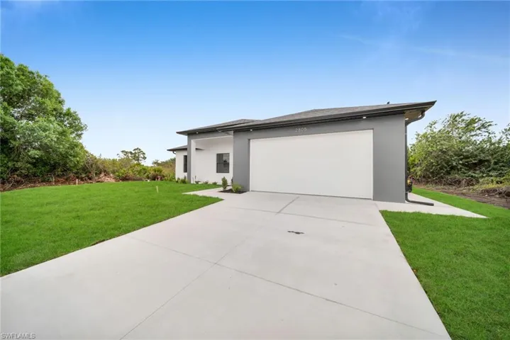 View of front of home featuring driveway, a garage, a front lawn, and stucco siding