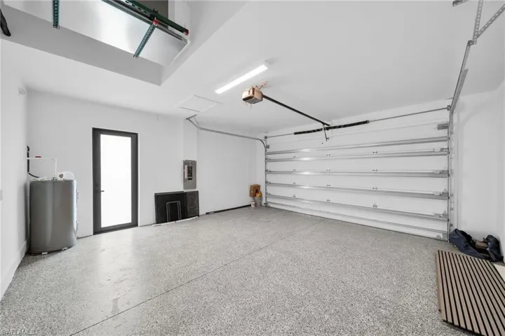 Garage featuring a garage door opener, electric panel, and water heater