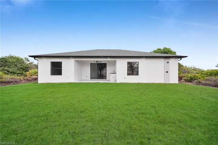 Rear view of property with stucco siding, ceiling fan, a patio, and a yard