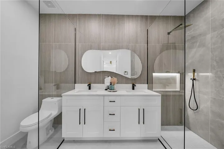 Full bathroom featuring a walk in shower, double vanity, a sink, and toilet