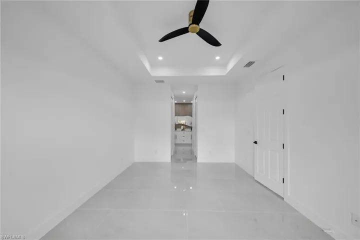 Empty room featuring baseboards, visible vents, a ceiling fan, a tray ceiling, and recessed lighting