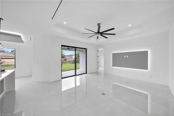 Spare room featuring ceiling fan, a tray ceiling, a wealth of natural light, and recessed lighting