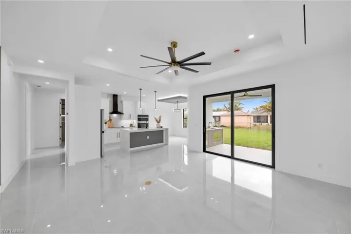 Unfurnished living room with baseboards, a raised ceiling, ceiling fan, marble finish floor, and recessed lighting