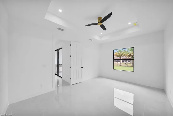 Spare room featuring a tray ceiling, visible vents, baseboards, and recessed lighting