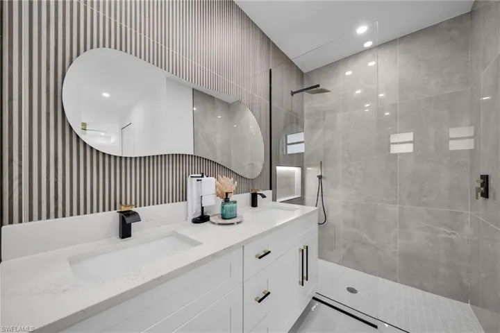 Bathroom featuring double vanity, walk in shower, and a sink