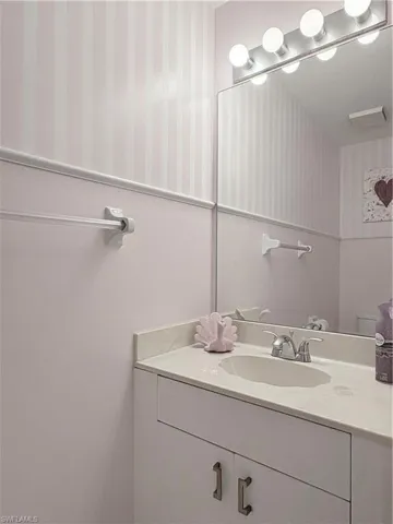 Bathroom featuring wallpapered walls and vanity