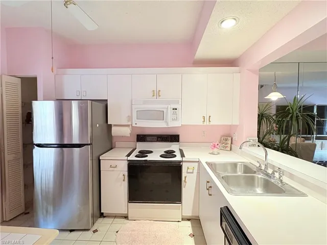 Kitchen featuring white appliances, a sink, white cabinetry, and light countertops