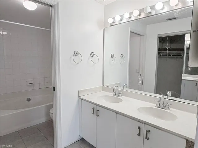 Bathroom featuring tile patterned flooring, double vanity, toilet, and bathtub / shower combination
