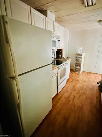 Kitchen featuring white cabinets, light hardwood / wood-style floors, and white appliances