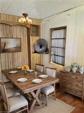 Virtually Staged: Dining space featuring hardwood / wood-style flooring, a notable chandelier, and wooden walls