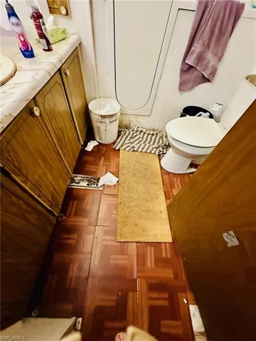 Bathroom with vanity, parquet floors, and toilet