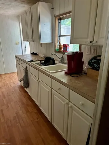Kitchen featuring sink, white cabinetry, and light hardwood / wood-style floors