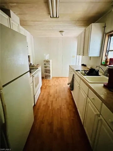 Kitchen featuring light hardwood / wood-style flooring, white appliances, and sink
