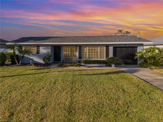Single story home with a garage and a lawn
