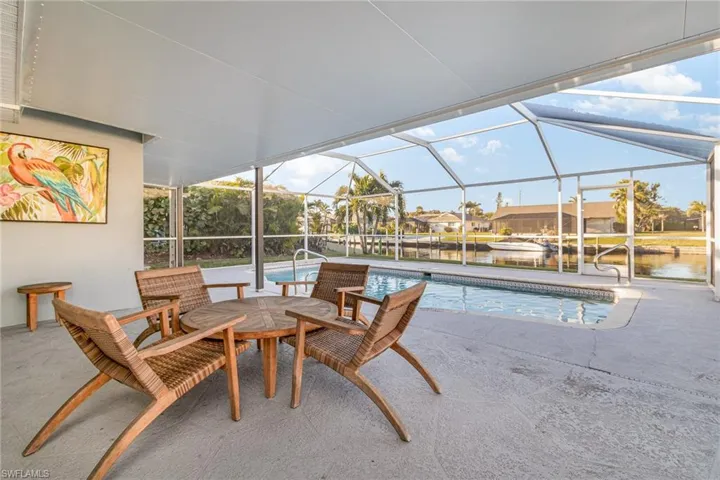 View of pool featuring a patio area, a water view, and glass enclosure