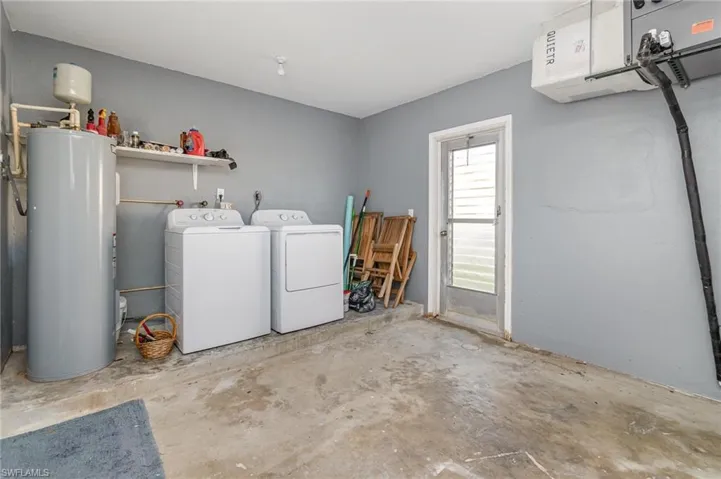 Laundry room with separate washer and dryer, electric water heater, and an AC wall unit
