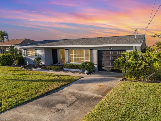 Ranch-style home featuring a garage and a lawn
