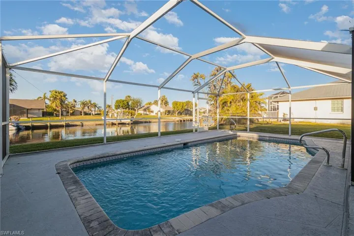 View of pool featuring a water view, a patio, and glass enclosure